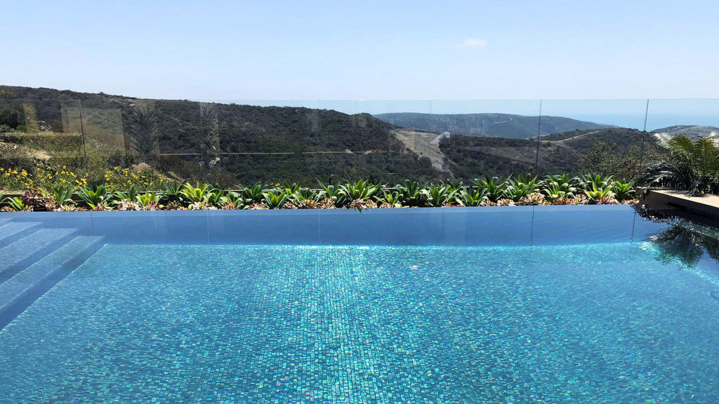 Beautiful, all-glass tile modern pool overlooking a forested mountain side.