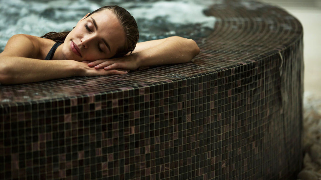 Woman relaxing by the edge of an infinity pool tiled in small-format tile by Trend.
