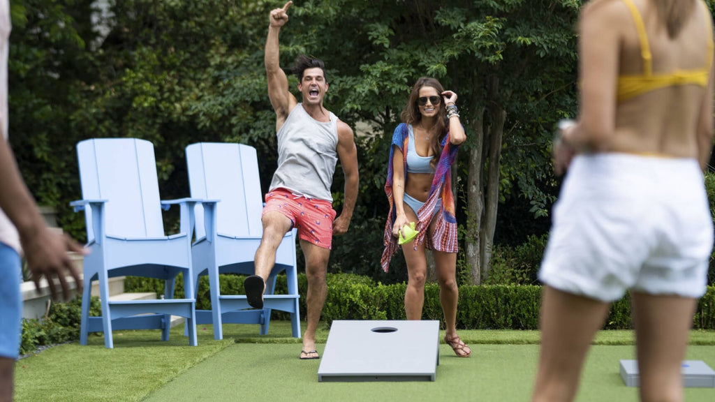Ledge Lounger cornhole set being played by young attractive couples in a stunning backyard.