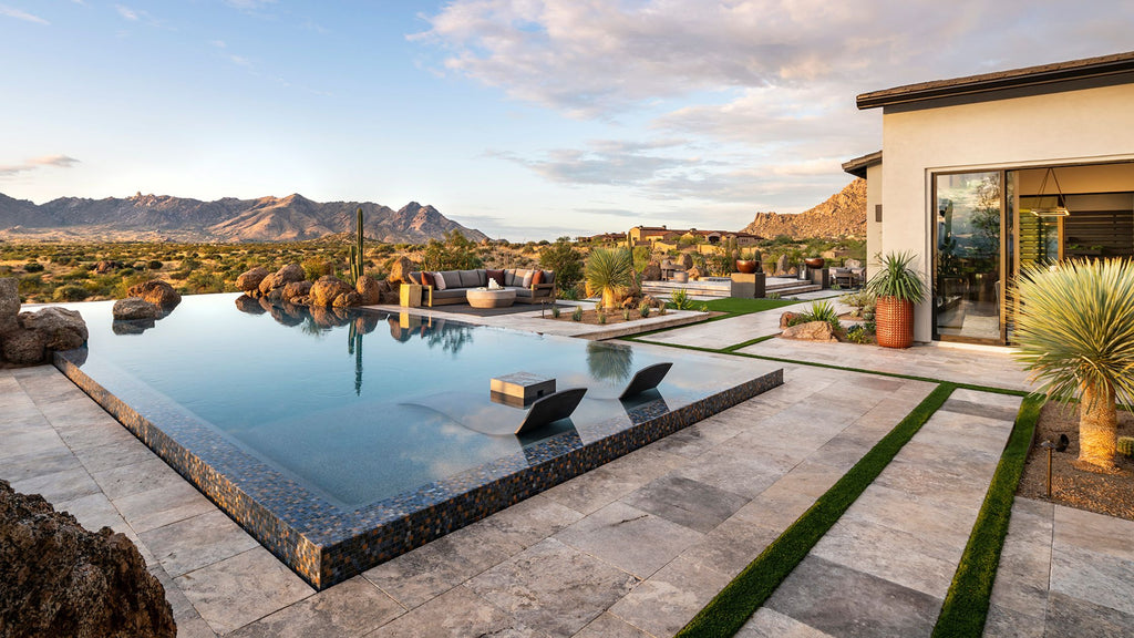 The Curve Chaise pool lounger in a rustic yet modern pool that looks out into the desert and the mountains.