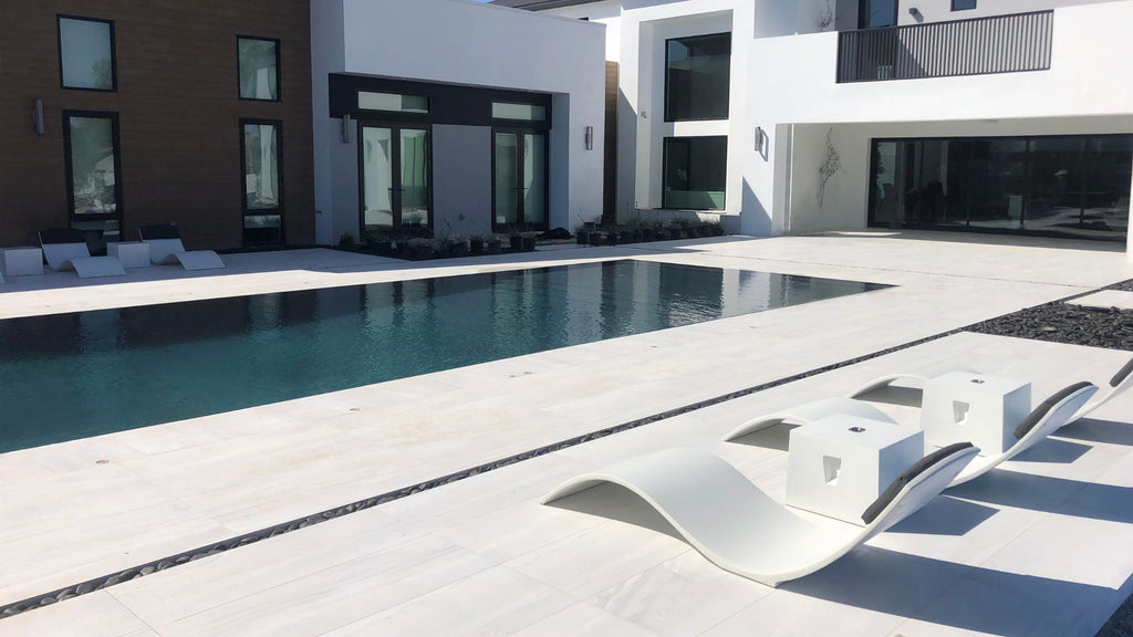 the Curve 2 chaise lounger on the pool deck of an ultra modern pool.