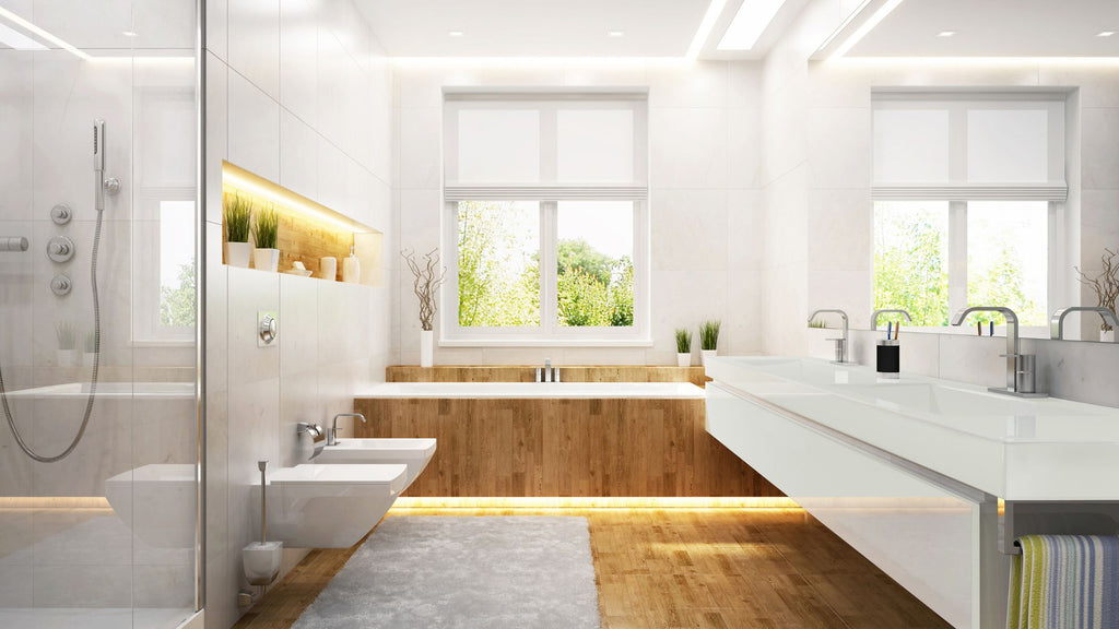 A beautiful, modern bathroom with a large window above a tub. The wood flooring extends up and around the tub surround and the walls and shower are tiled in a lovely off white color, large-format tile.