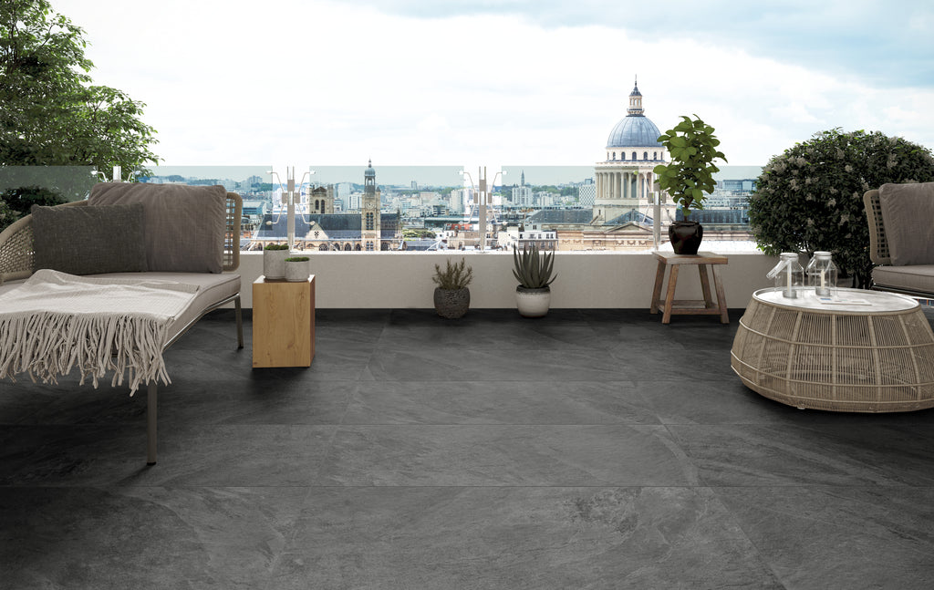 Beautiful, dark stone patio pavers used in a rooftop patio overlooking a cityscape.