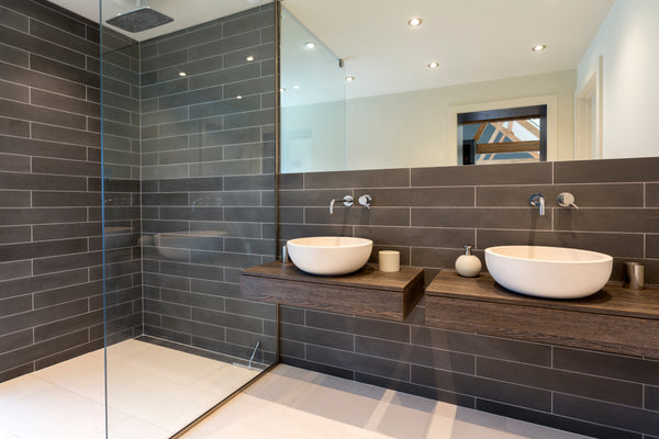 Photo of a sleek, modern bathroom with large format dark gray subway tile carried over from shower wall to the rest of the bathroom walls.