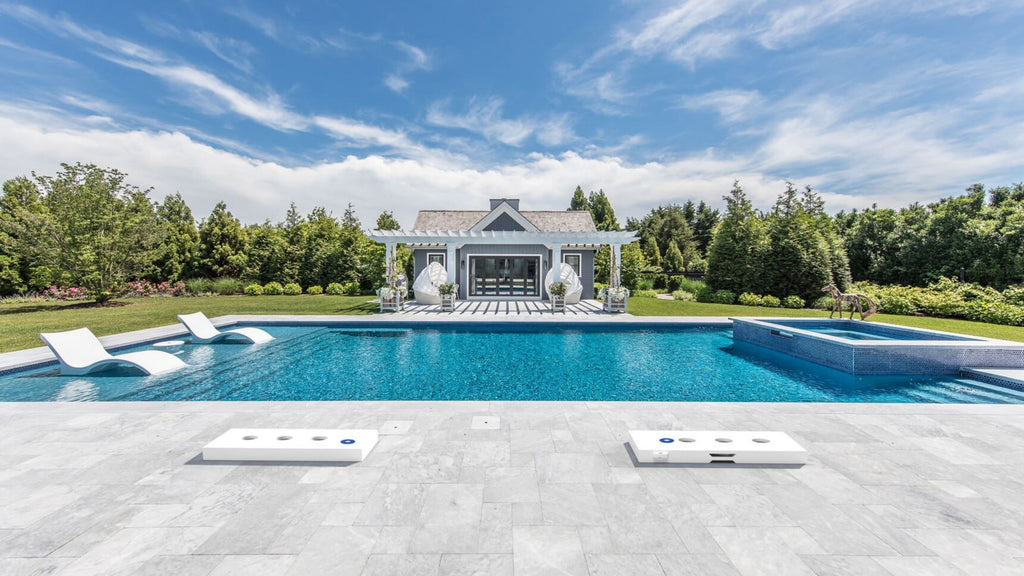 Ledge Lounger Washers Game Set by a beautiful luxury pool surrounded by stunning garden