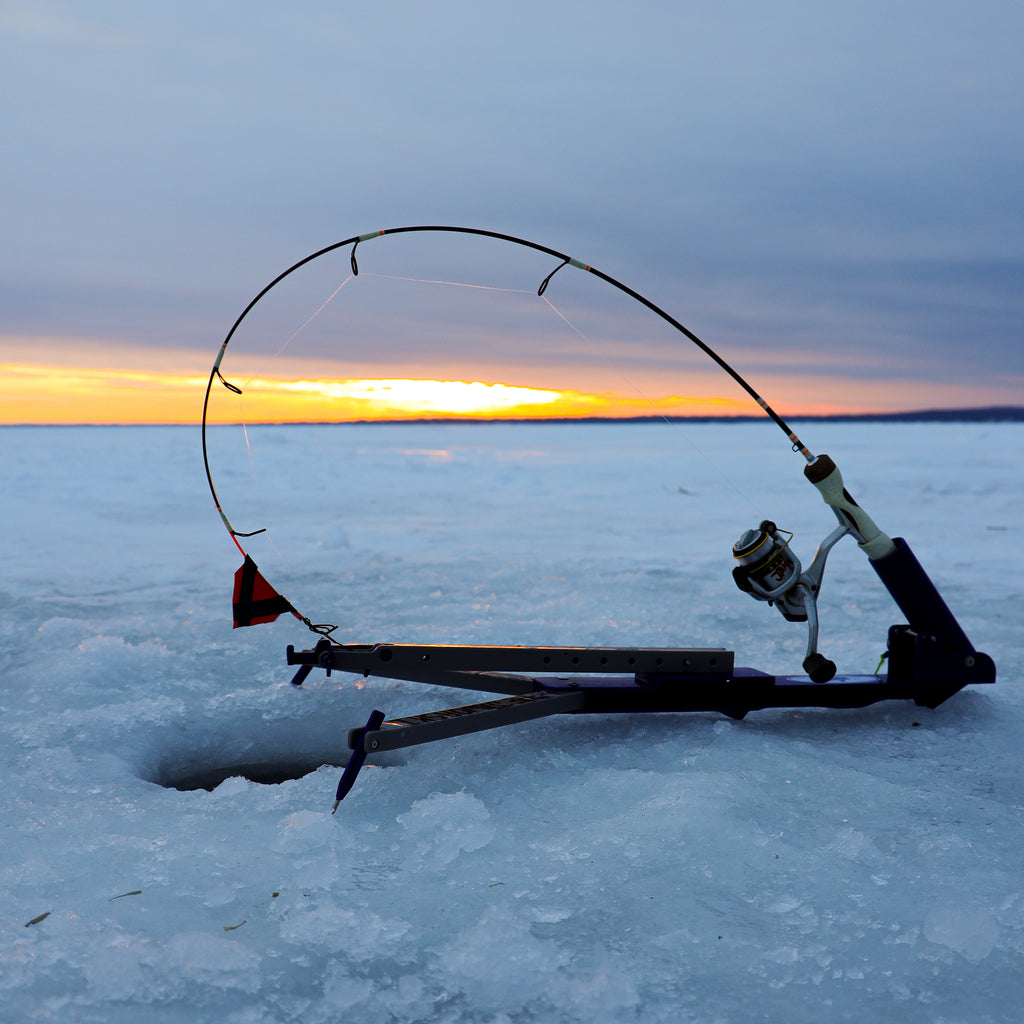 A LARGE TIP UP ICE FISHING LINE SITS OUT IN FRONT OF AN ICE HOUSE