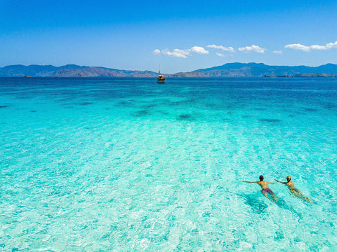 Aquamarine sea water with a couple of young people swiming