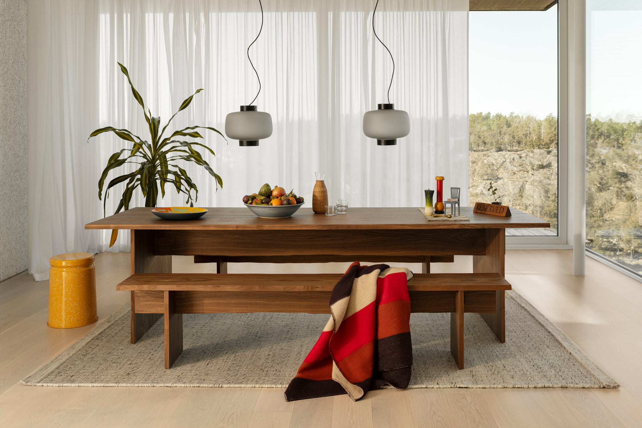 A Hem dining room scene featuring the Bookmatch Table + Bench Set in Walnut, Dusk Lamps, Dune Rug and Last Stool.