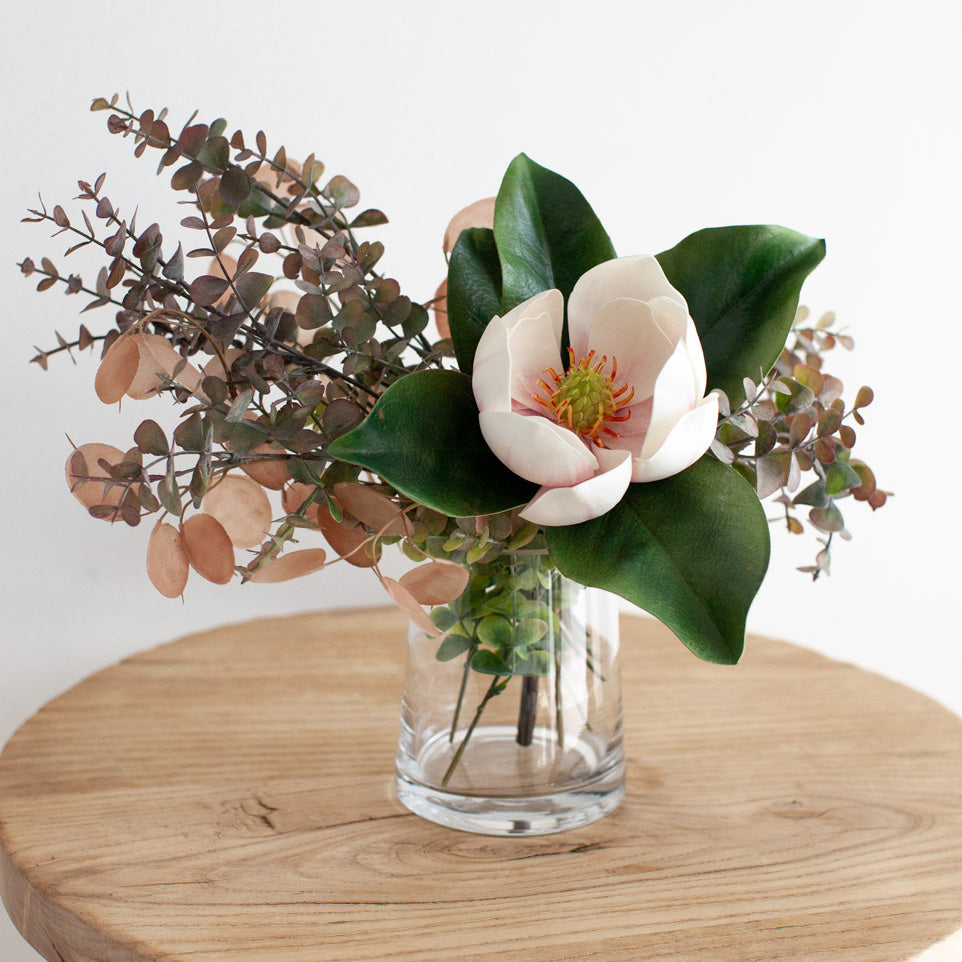 Artificial eucalyptus styled in a vase with a magnolia flower.