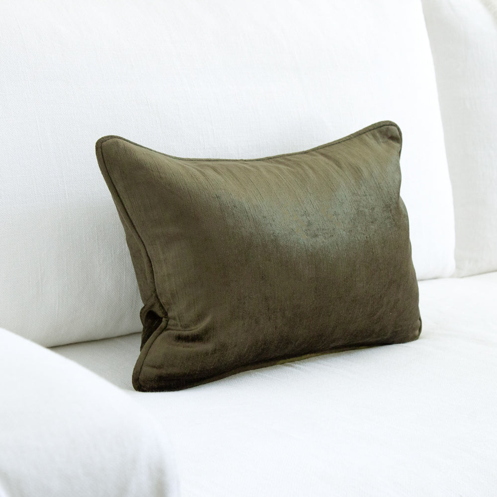 small dark green velvet cushion on white sofa