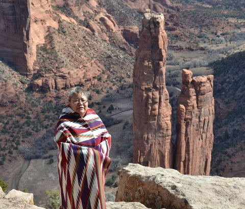 Cara Yassie wearing one of her weavings standing in front of Spider Rock