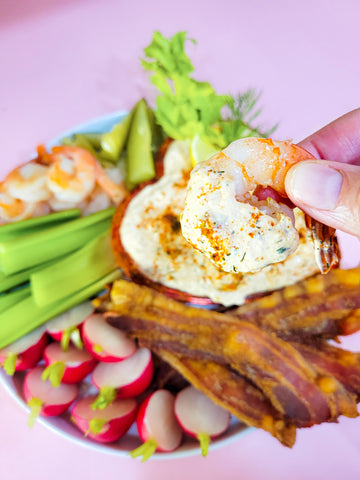 Hand holding shrimp dipped in Bloody Mary dip