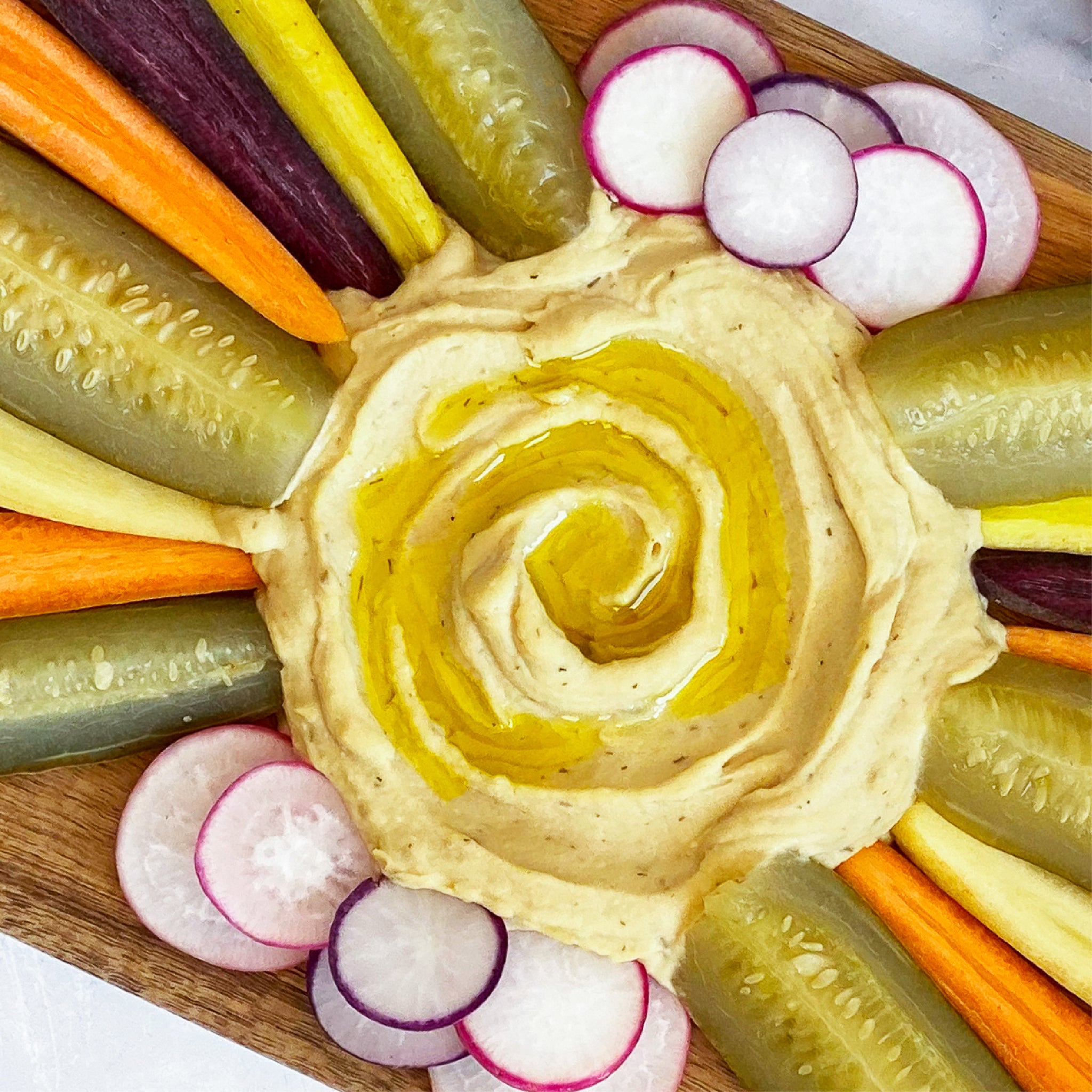 Board with carrots, pickles, radishes, and dill pickle hummus