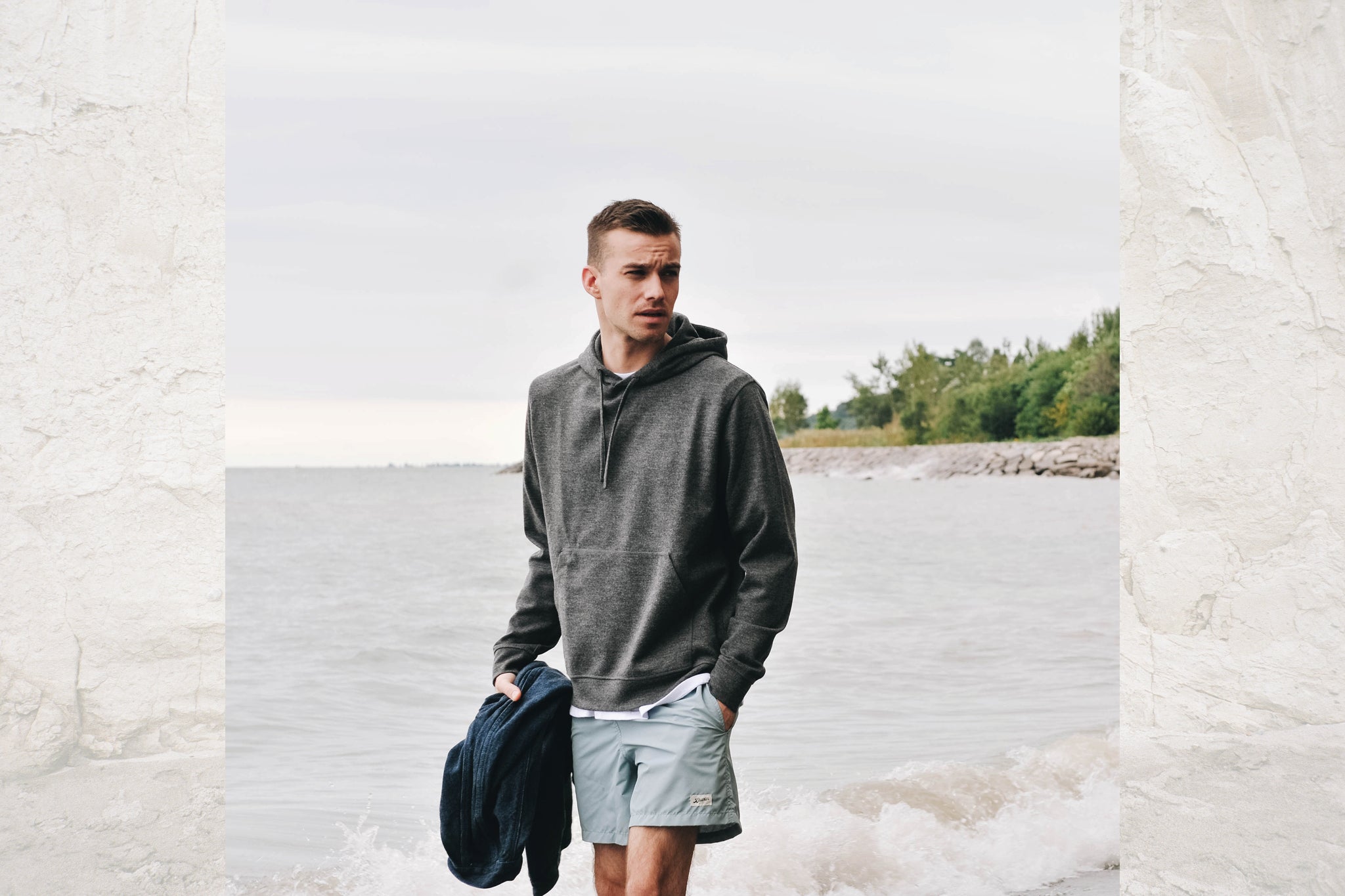 Man wearing swim trunks and a sweater on the beach