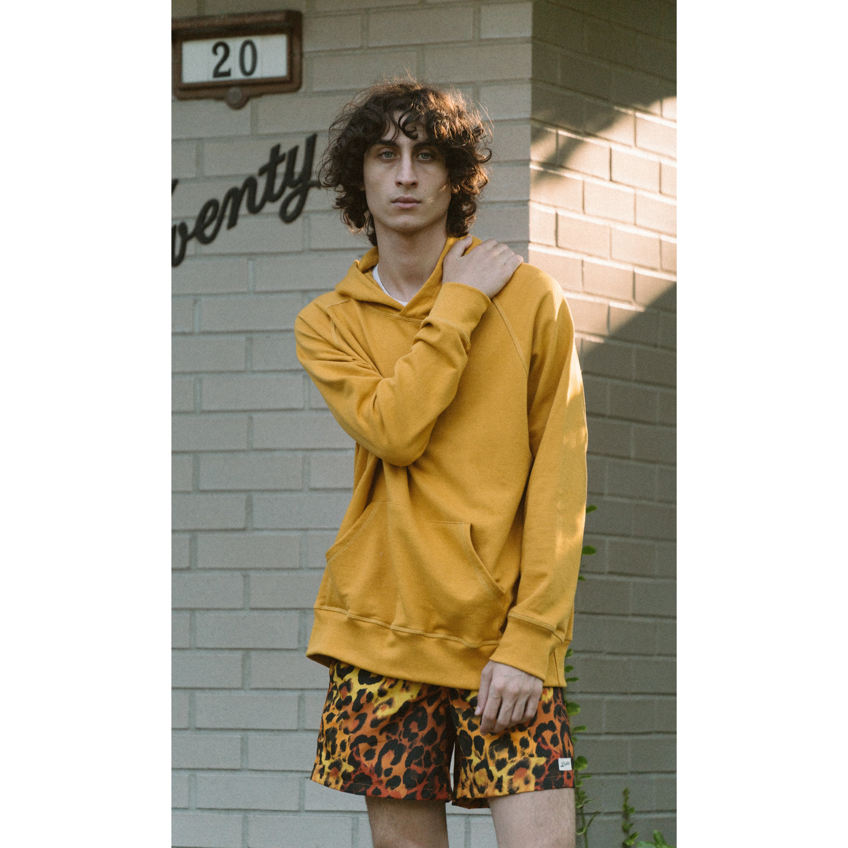 Model wearing Bather Tuscan Yellow hoodie and gold leopard swim trunks