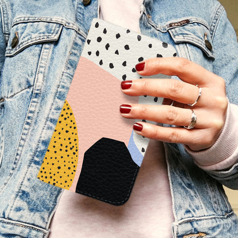 Abstract polka dot wallet phone case being held by a woman with red nail polish wearing a denim jacket