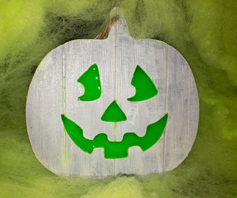 Wooden jack o' lantern sign placed within spooky green Halloween decor