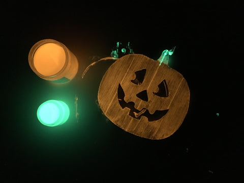 Freshly painted wooden jack o' lantern sign, lying next to orange and green glow in the dark paint 