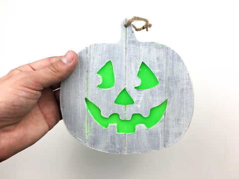 Holding the wooden jack o' lantern sign with yarn tied through the top