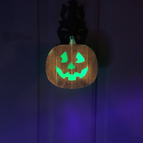 Wooden, glow in the dark jack o' lantern hanging on a door