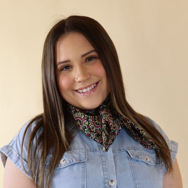 Brunette model is pictured wearing a Blue Dress with a Multicolored scarf tied around her neck. Model is pictured in front of a beige background. 