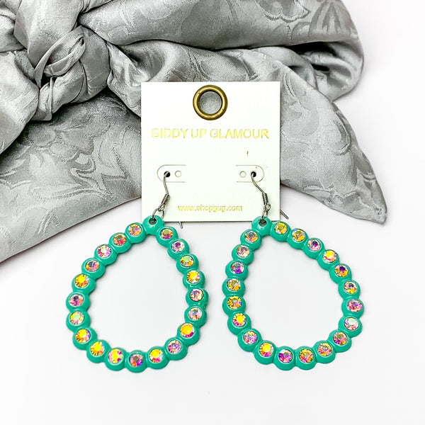 Open Teardrop Earrings with AB Crystal Outline in Turquoise. Pictured on a white background with silver fabric behind the earrings.