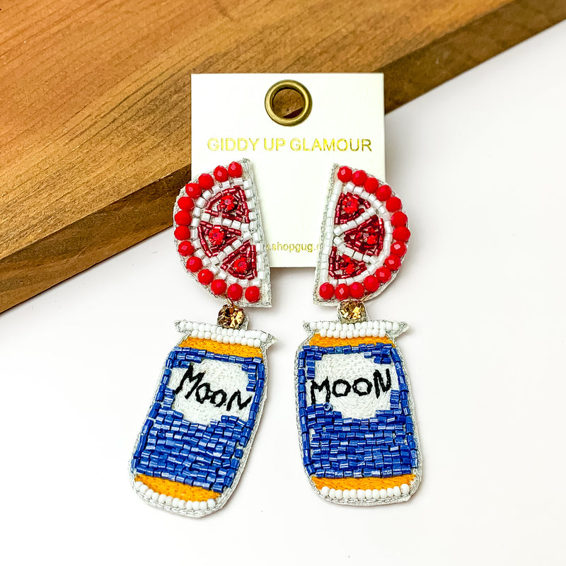 Beaded Blue Beer Can Earrings with Grapefruit Slice Studs. Pictured on a white background with a piece of wood at the top.