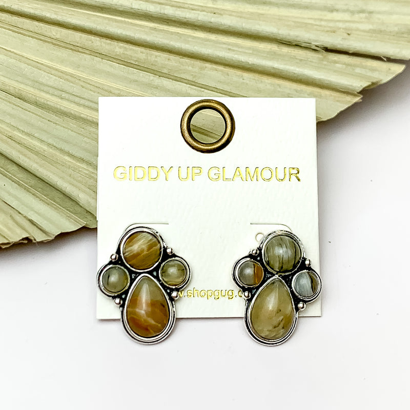Silver Tone Cluster Stone Earrings in Natural Brown. Pictured on a white background with a brown leaf fan behind the earrings.