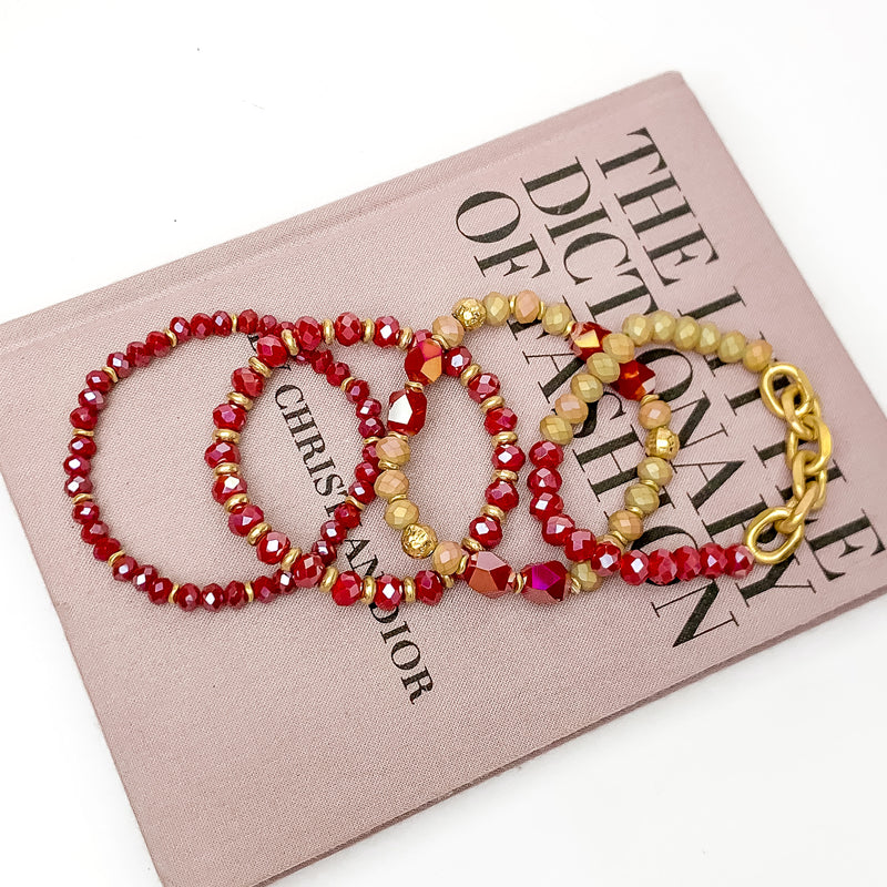 Set of Four | Glorious Gold Crystal Beaded Bracelet Set in Red. Pictured laying on a closed book. The book is on a white background.