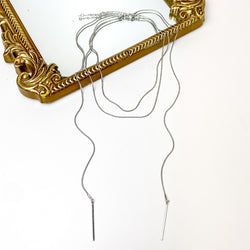 Wrap Around Necklace With Metal Accessory in Silver Tone. Pictured on a white background with part of the necklace laying on a mirror with a gold trim.