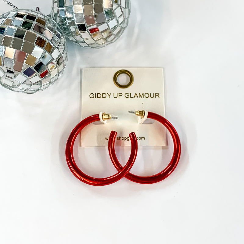Light Up Medium Neon Hoop Earrings In Red. Pictured on a white background with disco balls in the top left corner.