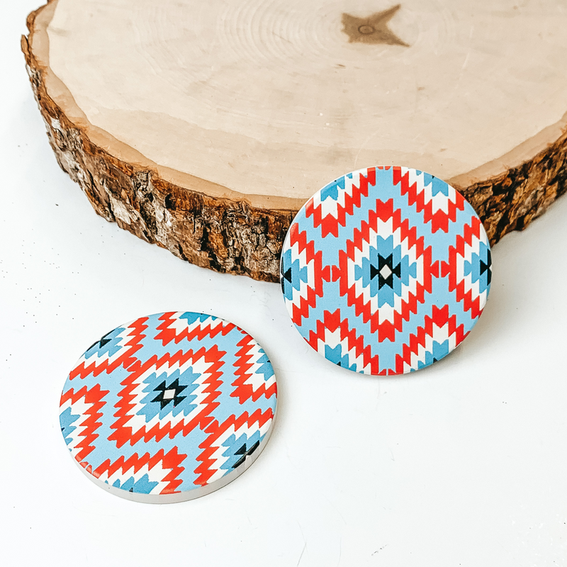 Set of two Tribal Print car coasters pictured on a piece of wood, with a white background. 