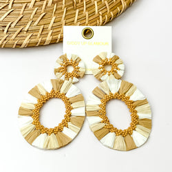 White and shades of tan open hoop earrings with tan beads on the inside. Pictured with a white background and wood decorations in the top left corner.