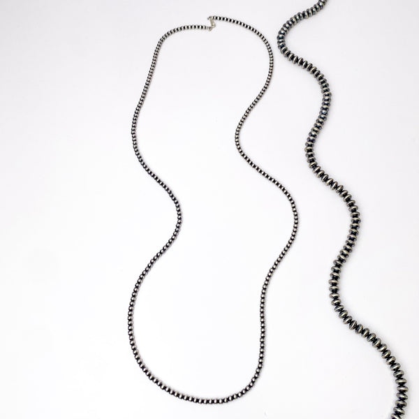 Centered in the picture is a long strand of navajo pearls on a white backdrop.