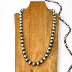 Centered in the picture is a large strand of navajo pearls on a wooden backdrop.