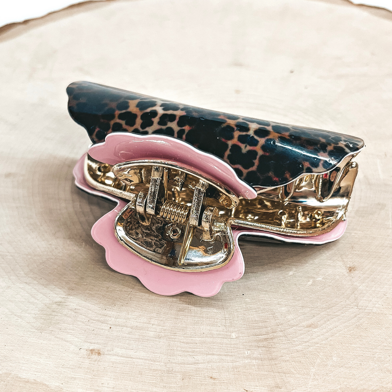 This is a dark leopard print hair clips with a gold tone inlay in light pink.  This hair clip is taken on a slab of wood and on a white background.