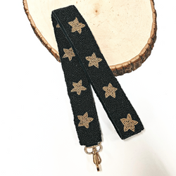 This is a black beaded purse strap with gold beaded stars all along with a gold clasp. This purse strap is taken on a slab of wood and on a white background.