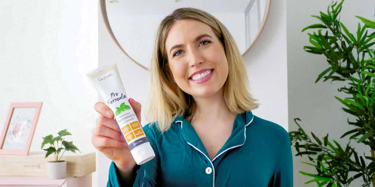 woman-smiling-holding-a-tube-of-oxyfresh-pro-formula-low-abrasion-toothpaste