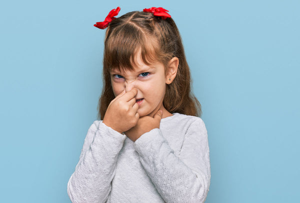 young girl plugging her nose looking grossed out