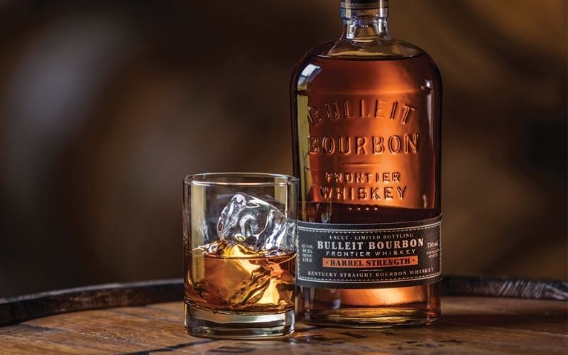 A bottle of Bulleit bourbon beside a glass