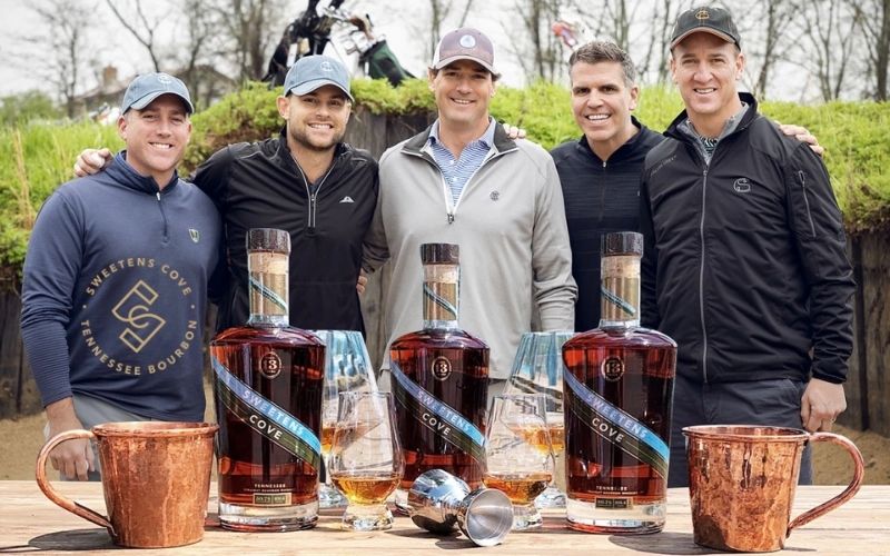 Nolan, Roddick, Collins, Rivers, and Manning with a table of their bourbon - Image by insidehook.com