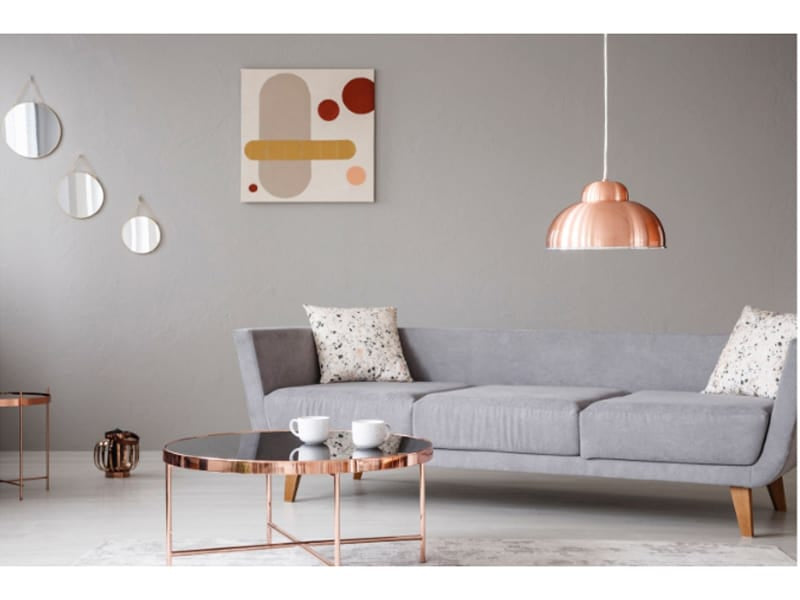  Copper lamp and coffee table in front of a modern sofa in a grey living room