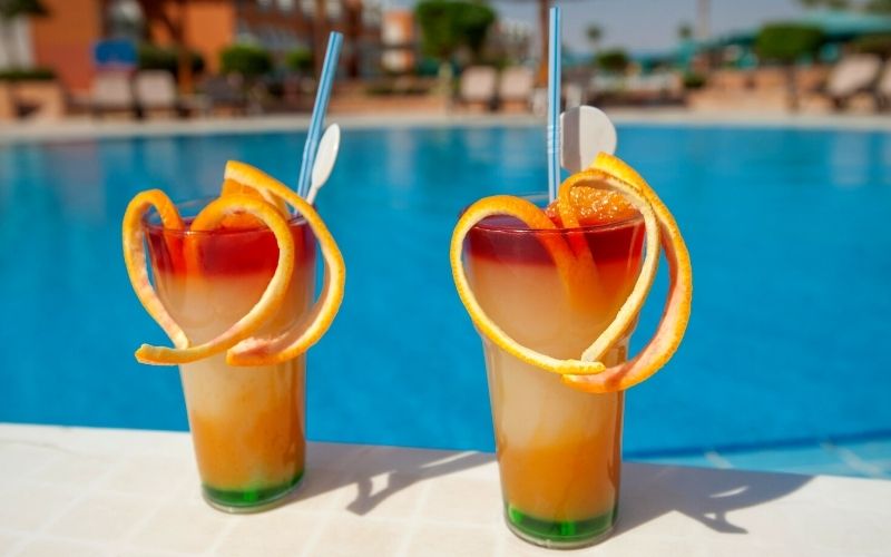 2 Glasses of layered cocktails beside the pool