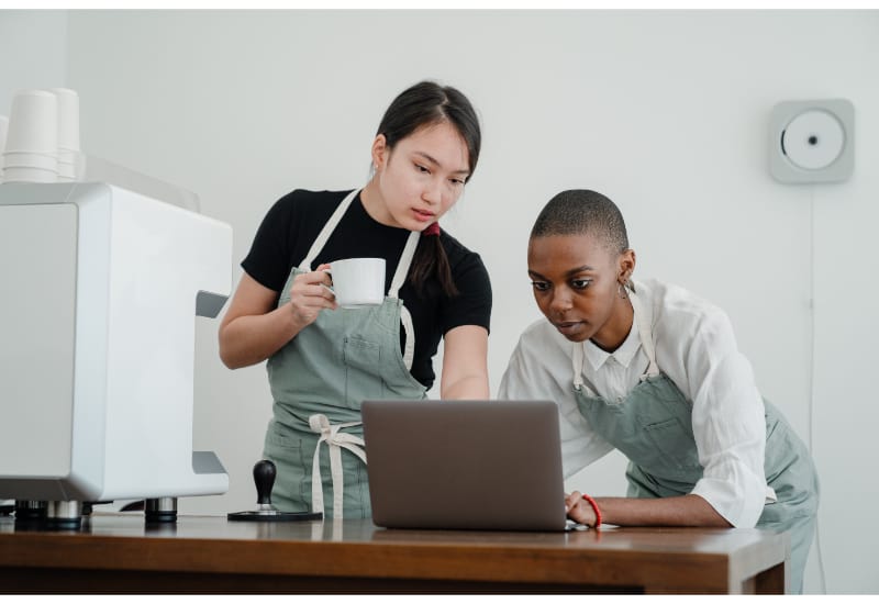 2 people in the kitchen looking up instructions on a laptop