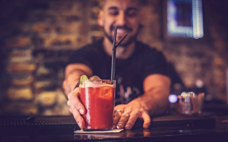 Bartender serving a glass of Bloody Mary