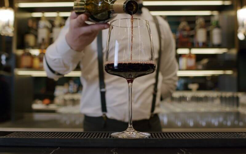 A bartender pouring a glass of wine