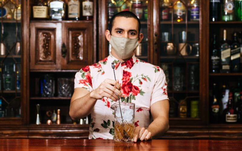 A bartender wearing a mask