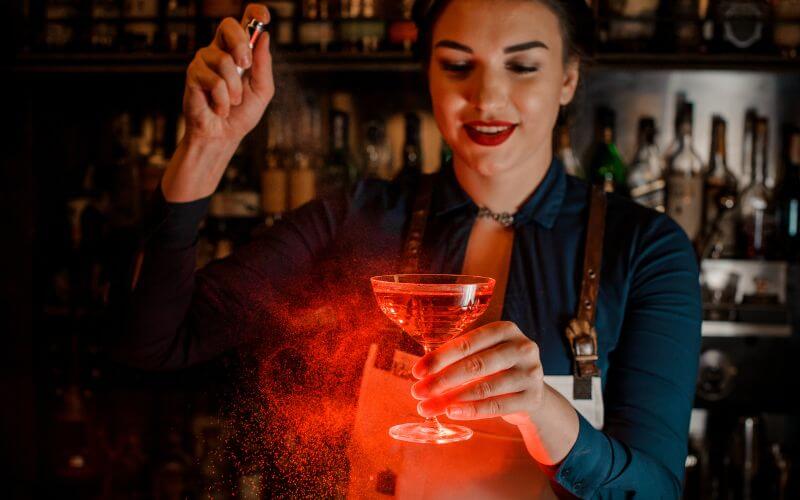 A female bartender serving flamed drinks