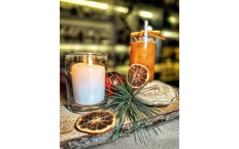 A glass of Orange Soul beside a candle and dehydrated oranges