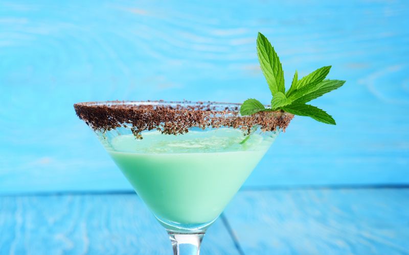 A glass of Bailey's mint martini on a light blue background